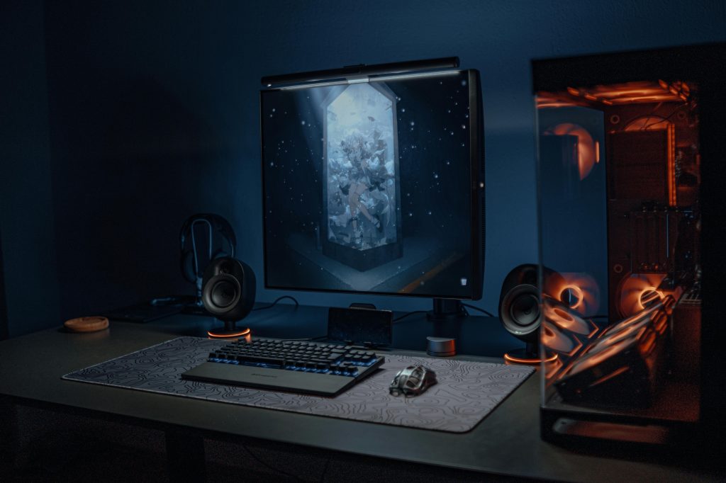 A stylish gaming setup featuring a screen, keyboard, and PC with ambient lighting.